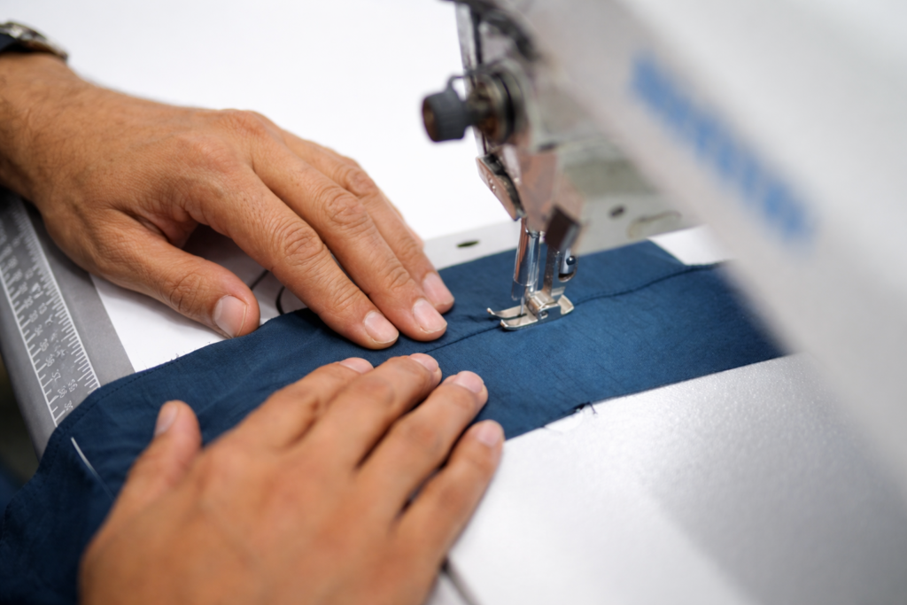 Worker stitching sportswear fabric on industrial sewing machine at Starlet International manufacturing facility in Pakistan